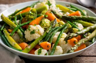 Para unosi się z bambusowego koszyka parowego pełnego świeżych warzyw i ryby